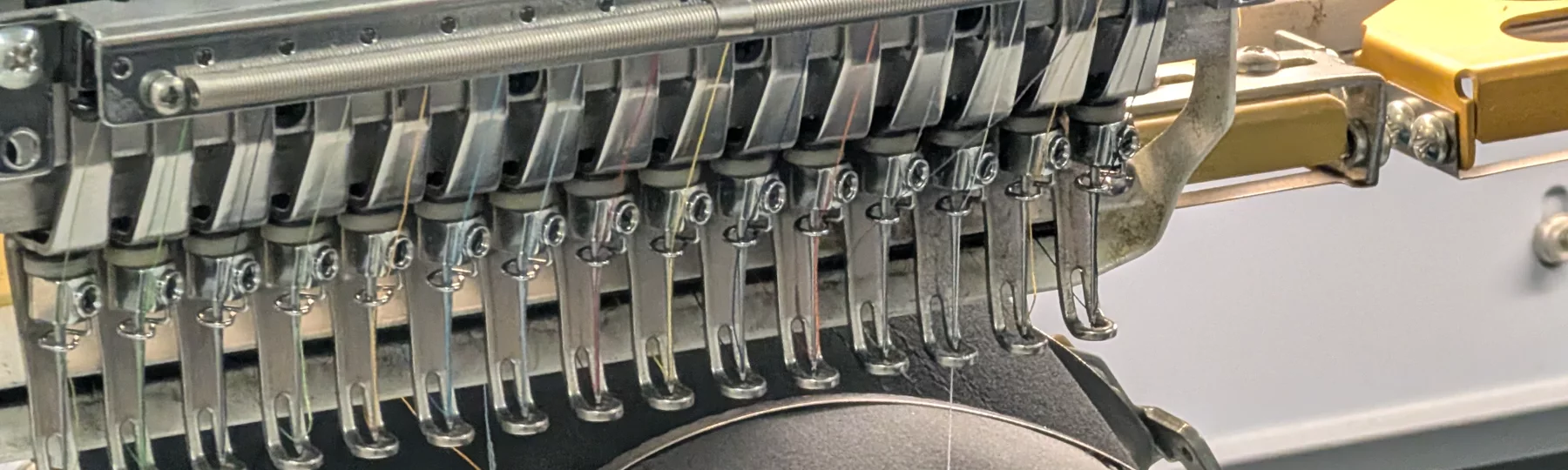 Close view of embroidery machine needles and thread at Del Print