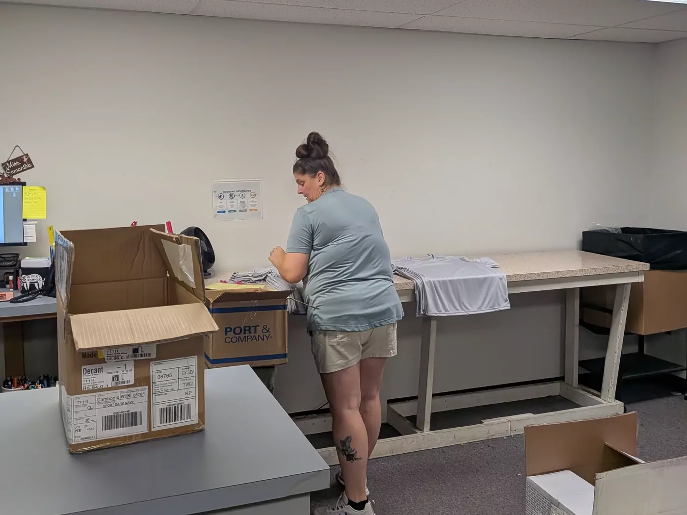 A Del Print employee folding and packing shirts at a workbench