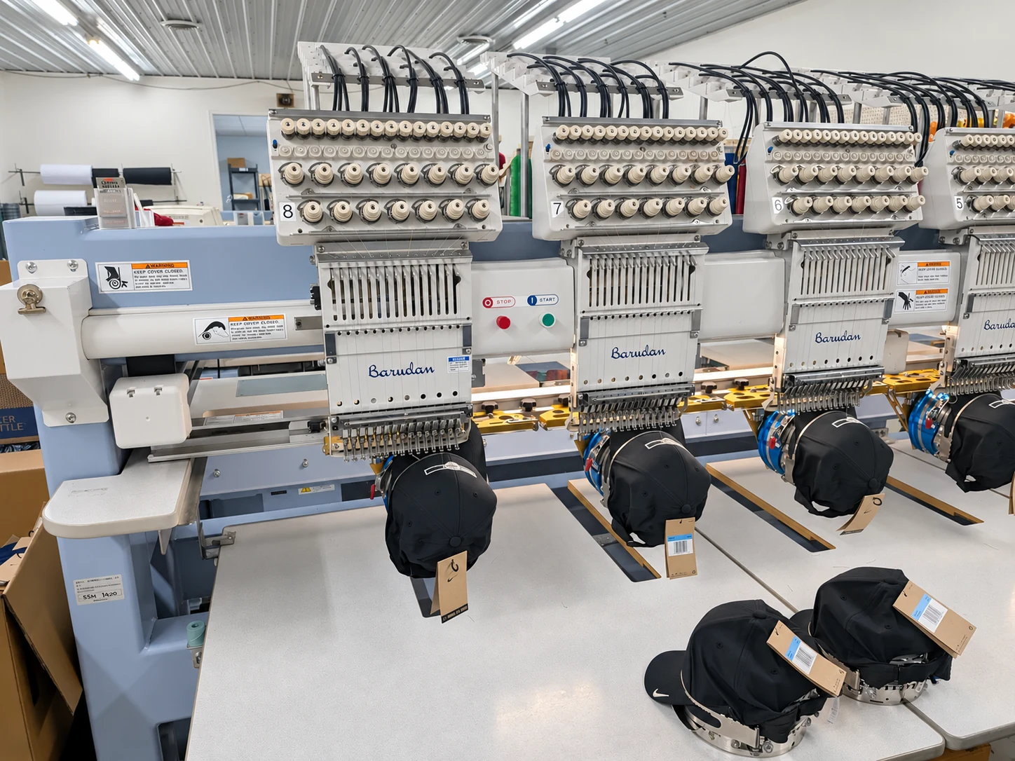 Edited photo: Caps mounted along a row of embroidery machines at Del Print