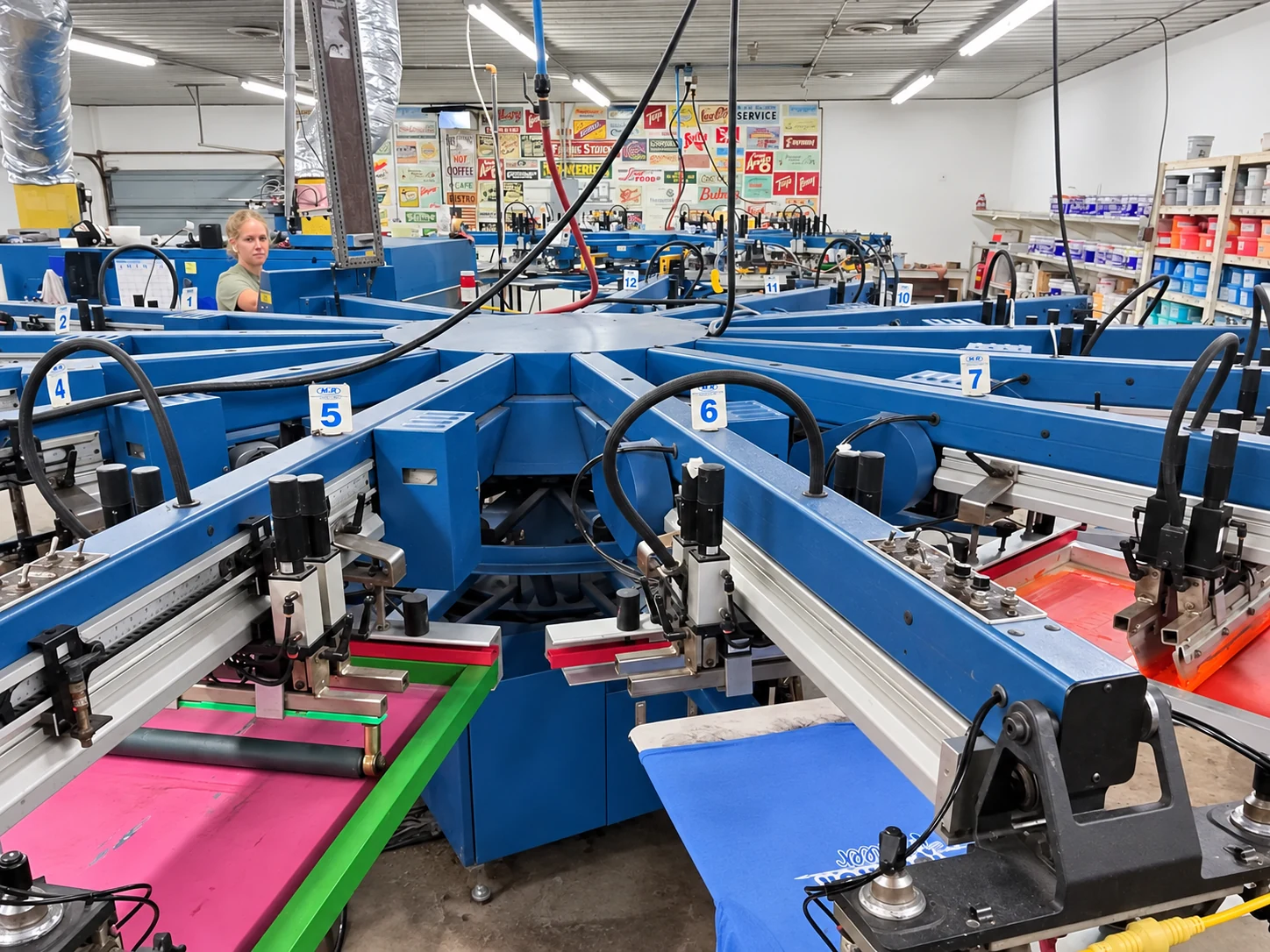 Edited photo: Close view across the blue press arms and shirt platens at Del Print