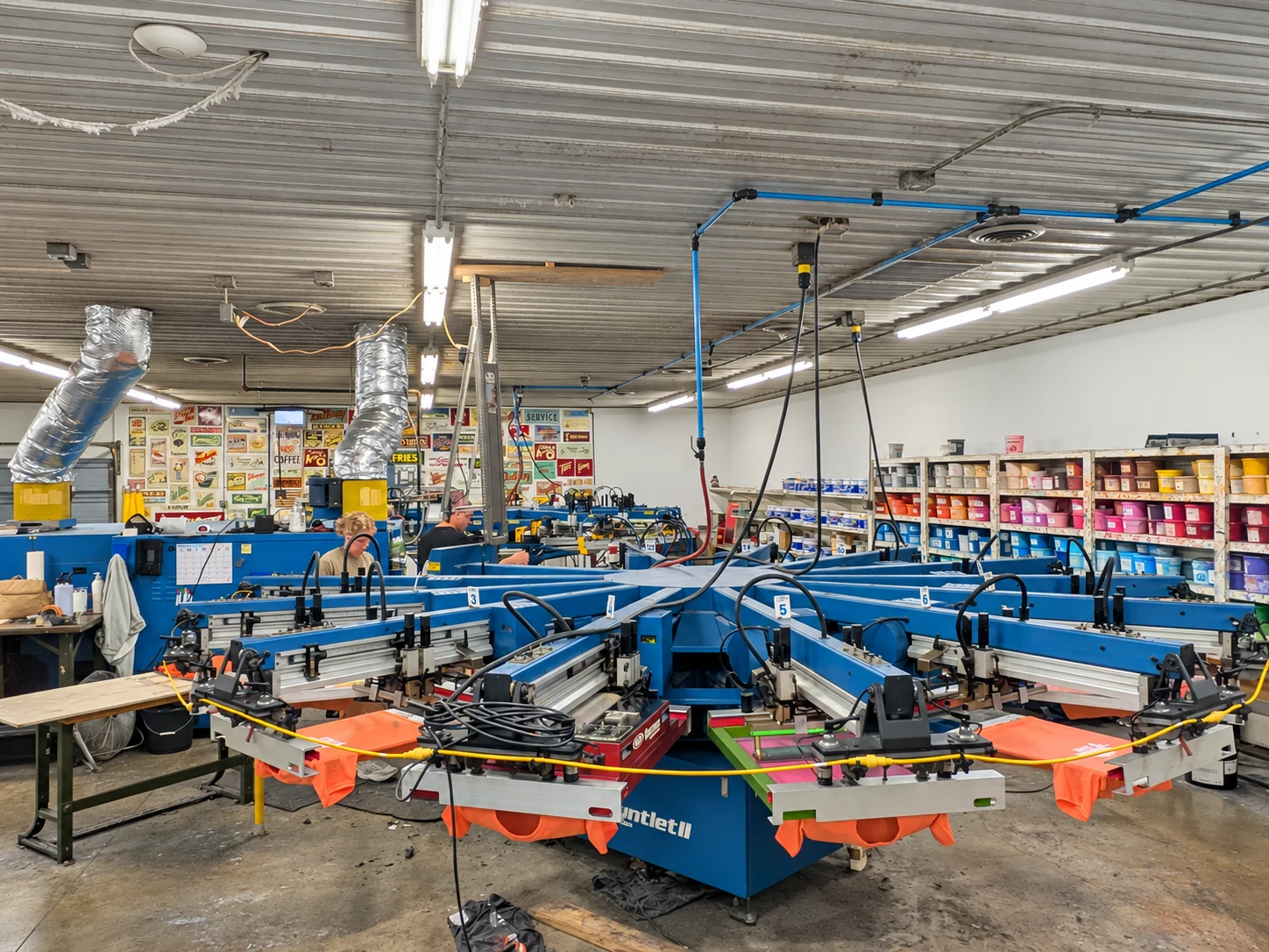 Edited photo: Orange garments on the printing presses inside Del Print’s shop