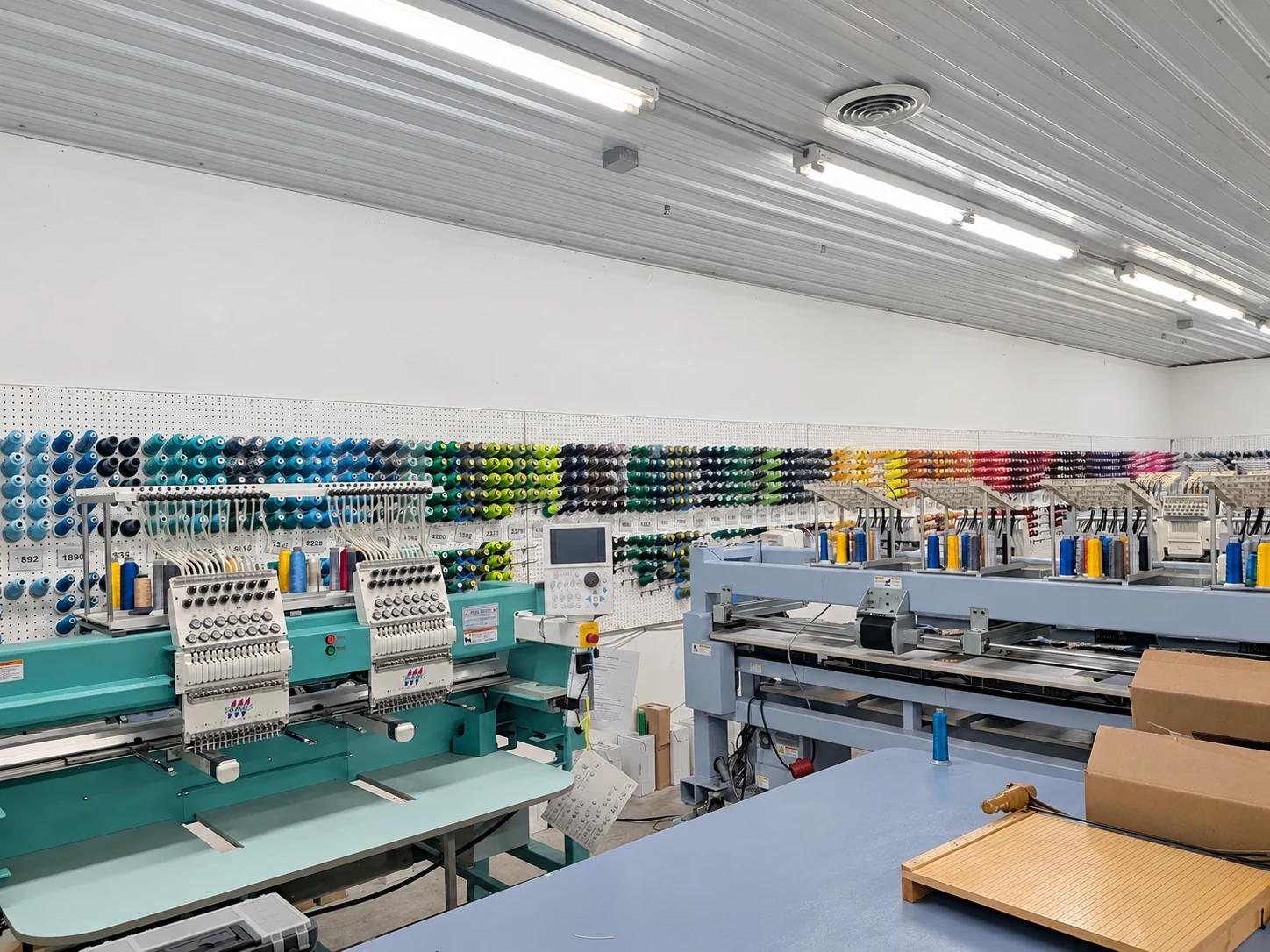 Edited photo: Colored thread and embroidery equipment inside Del Print’s embroidery department